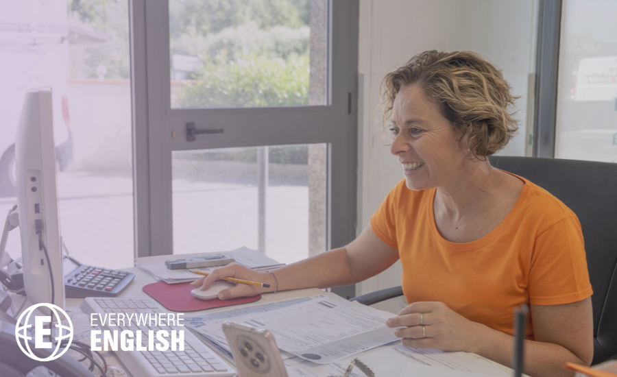 A professional woman smiling while drafting a business email on her computer.