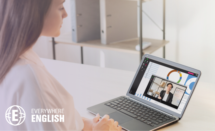 A woman sits at a desk, participating in a virtual Pharmaceutical English Training session on her laptop, displaying video call participants and graphs on the screen.