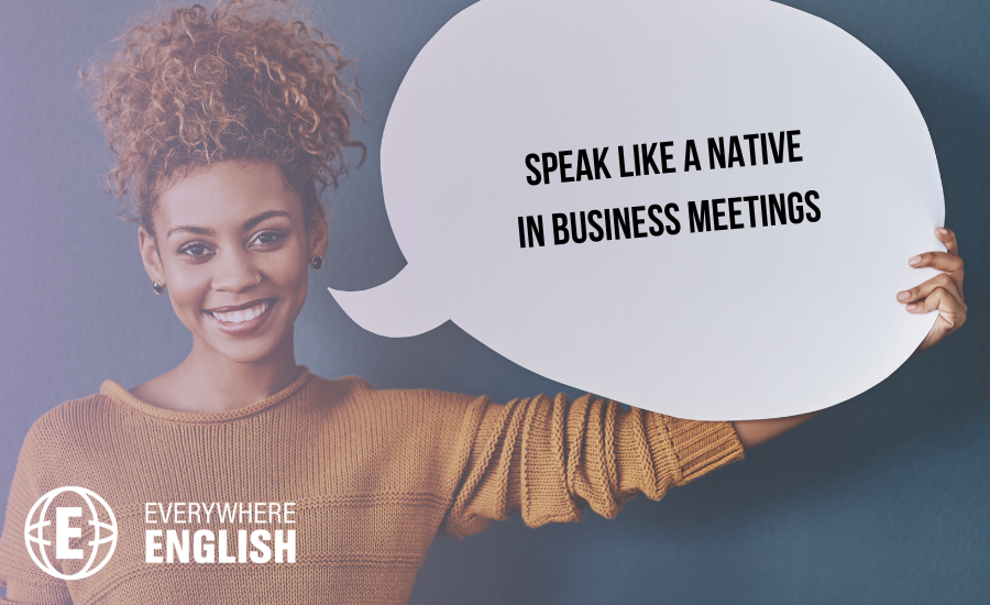A woman holding a speech bubble sign that reads, "Speak like a native in business meetings," stands against a plain background, highlighting the Top 20 Native Phrases to Use in Business Meetings for Effective Communication.